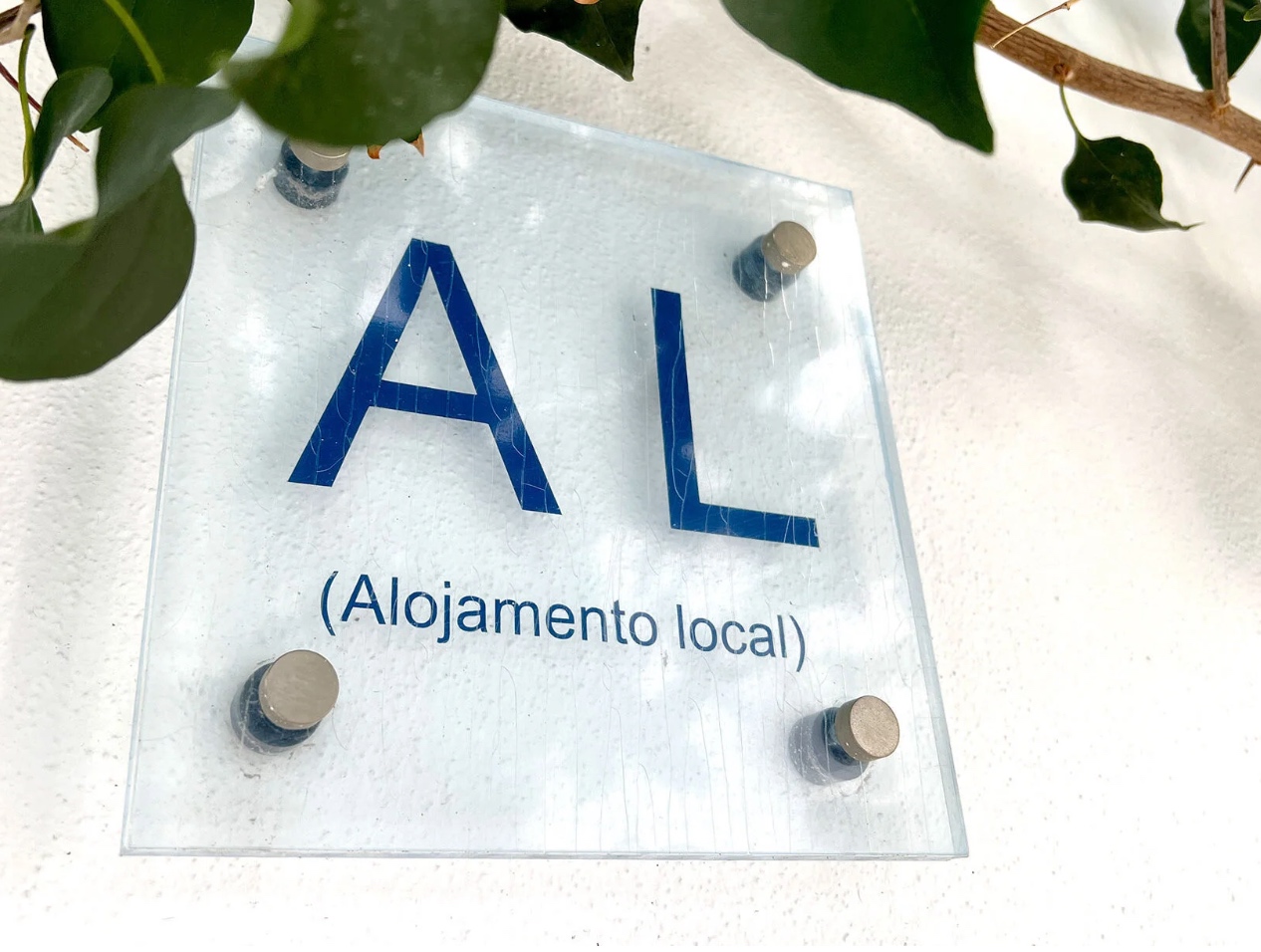 Alojamento Local plaque near a plant — AL registration is the first compliance step for Quarteira owners