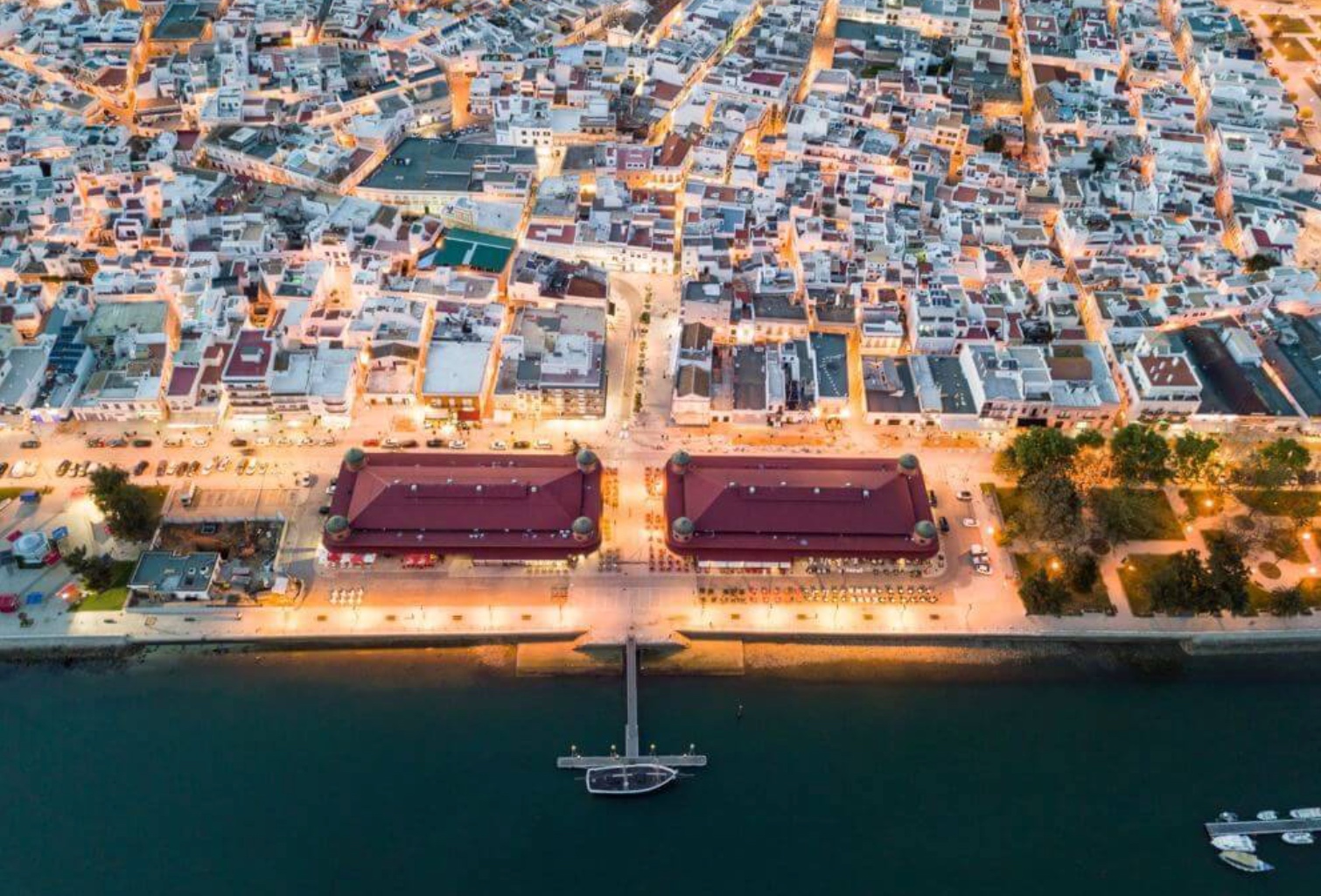 Vista aérea de Olhão à noite — panorama de conformidade no Algarve Oriental